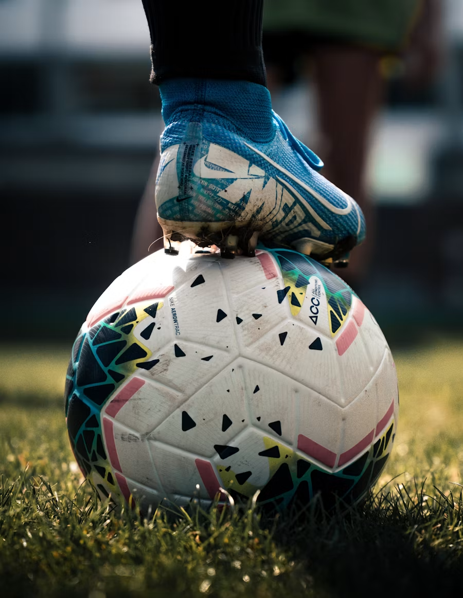 Jogador com a chuteira apoiada na bola antes de um treino
